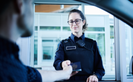 Photo of a BSO giving back a passport to a traveller - Photo d'une ASF redonnant un passeport à un voyageur